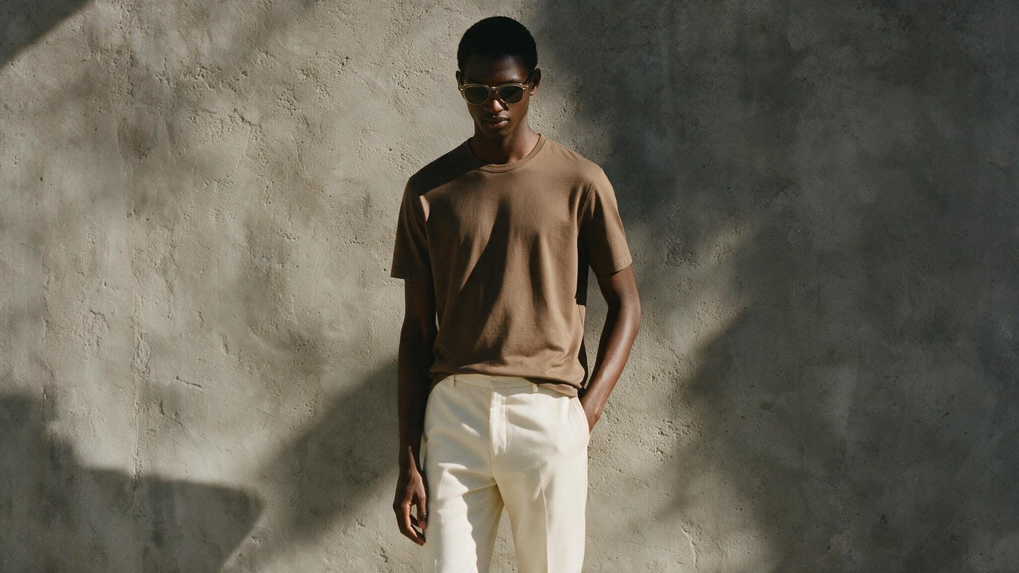 Scallero model wearing an olive crewneck t-shirt against a concrete wall